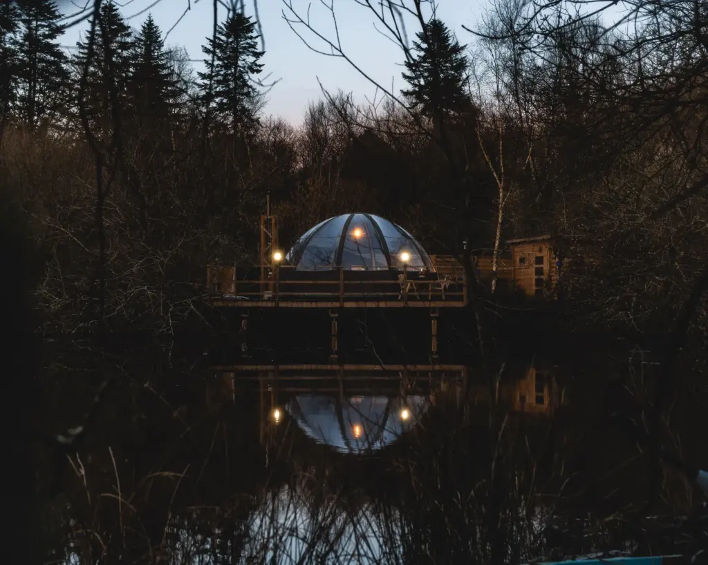 Domaine Rêves Étoilés : bulle éclairée la nuit au-dessus de l'étang
