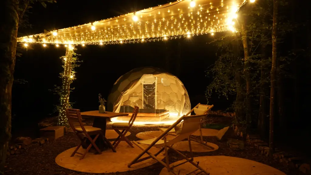 Ô Pays des Bois : coin salon sous les guirlandes lumineuses la nuit
